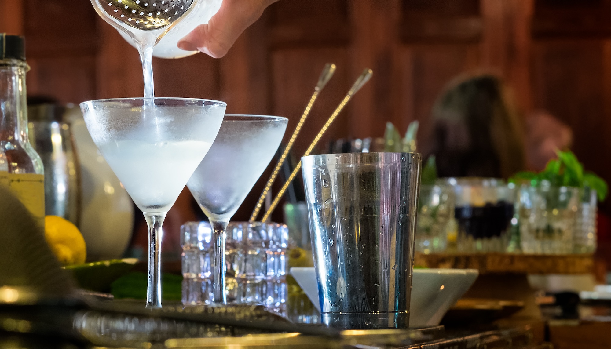 Bartender pouring handcrafted cocktails at a bar lounge.